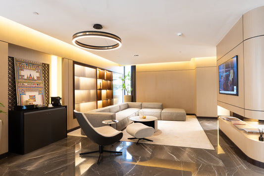 Modern office lounge with L-shaped sofa, accent chair, wall-mounted TV, and decorative wall art by Atelier 21 KSA, top interior designer in Saudi Arabia – صالة مكتب عصرية تحتوي على كنبة على شكل حرف L، كرسي مميز، تلفزيون مثبت على الحائط، ولوحة فنية ديكورية من تصميم مفن الرسام، أفضل مصمم داخلي في السعودية 7