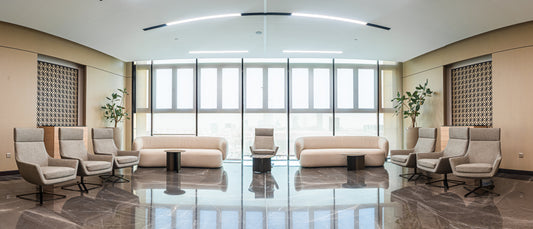 Modern office lounge with high-back chairs, beige sofas, marble flooring, and large windows by Atelier 21 KSA, top office furniture supplier in Riyadh – صالة مكتب عصرية تحتوي على كراسي بظهر مرتفع، كنبات بيج، أرضية رخامية، ونوافذ كبيرة من تصميم مفن الرسام، أفضل مورّد أثاث مكتبي في الرياض 14