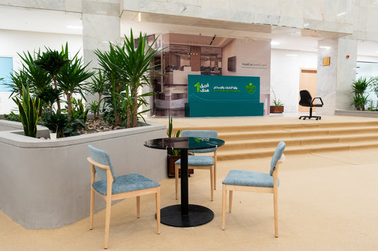 Casual waiting area with light blue upholstered chairs and round black glass table near Ministry of Municipal and Rural Affairs & Housing desk – indoor greenery and modern marble interior – منطقة جلوس غير رسمية بكراسي منجدة بلون أزرق فاتح وطاولة زجاجية أمام مكتب وزارة الشؤون البلدية والقروية والإسكان – ديكور رخامي حديث ونباتات داخلية 31