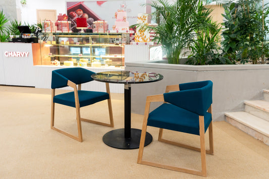 Contemporary café seating with teal upholstered chairs and glass-top table in front of Charvy dessert counter – stylish setup by Atelier 21 KSA – جلسة مقهى عصرية بكراسي منجدة بلون أزرق زمردي وطاولة بسطح زجاجي أمام واجهة حلويات شـارفي – تصميم أنيق من مفن الرسام 30