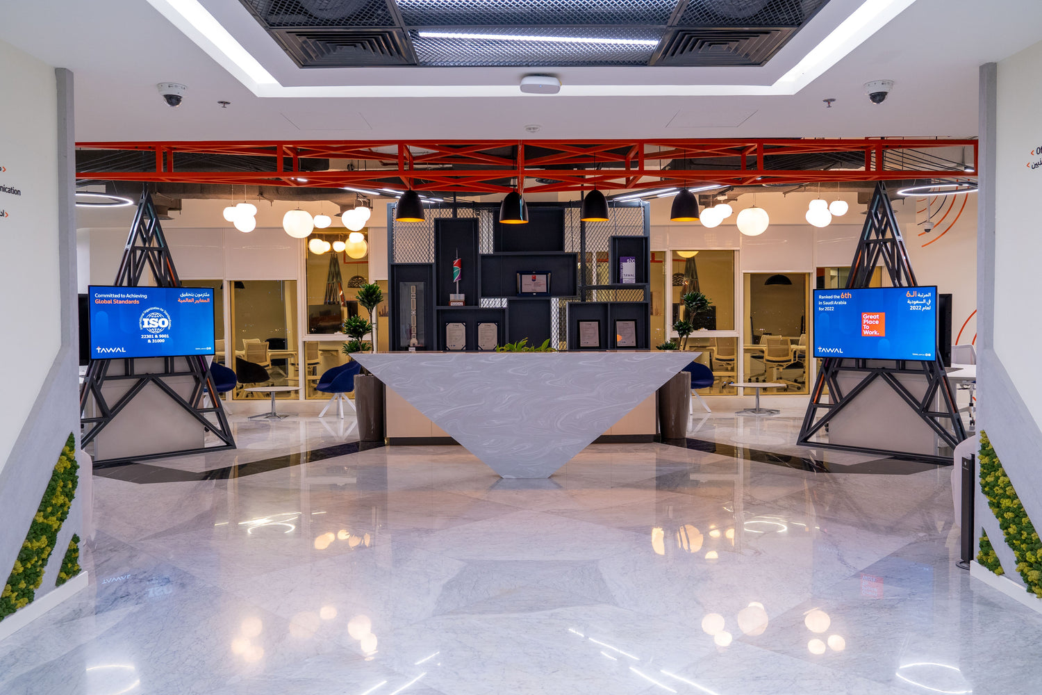 Tawal reception area – modern and innovative design with a sculptural reception desk, geometric shelving, digital displays, and smart lighting – reflecting a high-tech identity in a corporate setting – project by Atelier 21 KSA, Top Interior Fit-out Company in Saudi Arabia and Riyadh. مكتب استقبال شركة TAWAL – تصميم معاصر يجمع بين الأناقة والتكنولوجيا، مع مكتب استقبال هندسي وشاشات ذكية وإضاءة مبتكرة – من تنفيذ مفن الرسام، أفضل شركة تصميم داخلي في السعودية والرياض.