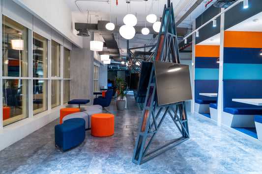 Creative breakout area featuring soft seating, wall booths, and vibrant ottomans in blue, grey, and orange—designed for collaboration and informal meetings, part of Kimera interior project by Atelier 21, top interior fit-out company in Saudi Arabia.
منطقة استراحة إبداعية تضم مقاعد مريحة، مقصورات جانبية، ووسائد ملونة بالأزرق والرمادي والبرتقالي – مصممة للتعاون والاجتماعات غير الرسمية – من تنفيذ مشروع كيميرا الداخلي بواسطة مفن الرسام، أفضل شركة تصميم داخلي بالسعودية. 21