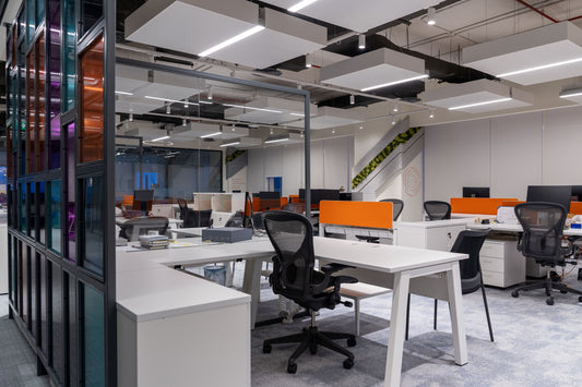 Modern open-space office interior with ergonomic task chairs, white workstations, and vibrant orange privacy panels – acoustic ceiling panels and glass partitions enhance functionality and design – ideal for creative tech environments – implemented by Atelier 21, Top Interior Fit-out Company in Saudi Arabia and Riyadh. مكتب مفتوح حديث بتصميم مريح وألوان جريئة – تنفيذ مفن الرسام، أفضل شركة تصميم داخلي وتنفيذ مكاتب في السعودية والرياض. 16