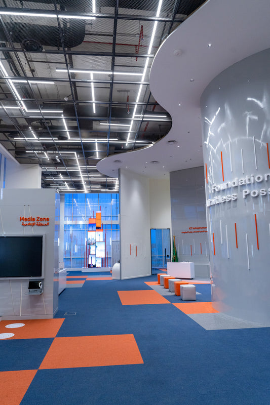 Modern interior with curved architecture, digital media displays, and bold ceiling lighting—featuring orange and blue flooring. Designed by Atelier 21 KSA, a Top Interior Fit-out Company in Saudi Arabia and Riyadh.
تصميم داخلي عصري يتميز بانحناءات معمارية، شاشات رقمية، وإضاءة سقفية ملفتة، وأرضيات باللونين البرتقالي والأزرق – من تنفيذ مفن الرسام، أفضل شركة تصميم داخلي وتشطيب مكاتب في السعودية والرياض. 5