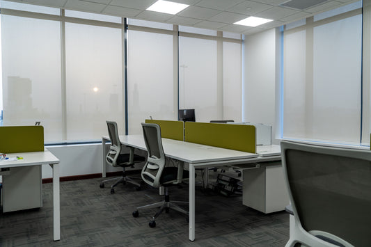 Modern open-plan office space at the Welaya project in Riyadh. White workstations with olive green privacy panels, ergonomic office chairs, and floor-to-ceiling windows with daylight filtering shades. تصميم مكتبي مفتوح في مشروع ولاية بالرياض، محطات عمل بيضاء، فواصل خصوصية خضراء، كراسي مريحة، نوافذ ممتدة تسمح بدخول الضوء الطبيعي، بيئة عمل حديثة وعصرية في قلب الرياض. 7