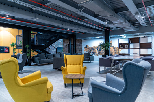 The Misk Foundation project in Riyadh features a creative lounge space with bright yellow and grey lounge chairs, soft seating, and an inviting library area. The industrial-style ceiling with exposed ductwork blends with warm wooden floors and creative wall art, creating a balance of innovation and comfort. يجمع مشروع مؤسسة مسك في الرياض بين الراحة والإبداع في تصميم مفتوح مع أثاث مريح وجدران فنية تعكس روح المدينة. 3