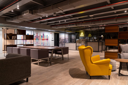 The Misk Foundation project in Riyadh features a cozy yet modern coworking zone with lounge seating, a sleek wooden meeting table, and a trendy café corner. Pops of yellow and neutral tones balance warmth and professionalism. A colorful Riyadh skyline mural enlivens the backdrop. مشروع مؤسسة مسك في الرياض يجمع بين الأناقة والراحة، بمناطق عمل مشتركة، وألوان حيوية، وجداريات تعكس طابع المدينة. 2