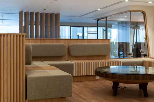 Stylish breakout seating area at Azm Saudi Project, featuring modern cushioned benches, wooden paneling, and a round glass coffee table for collaboration and relaxation. Designed by a Top Interior Designer in Riyadh and furnished by a Top Furniture Supplier in Saudi Arabia, the space blends comfort with contemporary aesthetics. منطقة استراحة حديثة في مشروع عزم السعودية من عمل أفضل مصمم داخلي في السعودية وتشطيب من أفضل شركة تنفيذ تشطيبات داخلية في الرياض. 6
