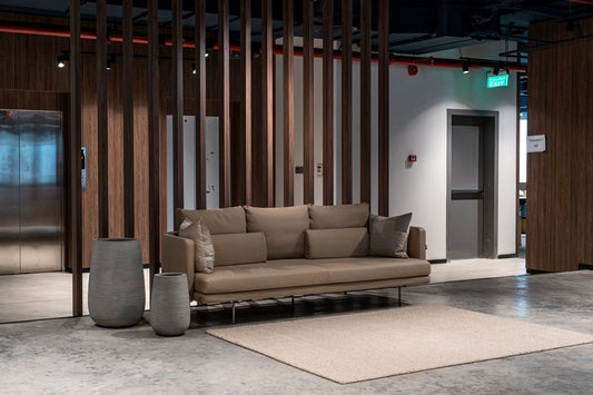 Stylish reception lounge at Azm Saudi Project featuring a modern beige sofa, decorative vases, and wood partition wall, reflecting contemporary office design. Executed by a Top Interior Designer in Riyadh and furnished by a Top Furniture Supplier in Saudi Arabia, the space enhances hospitality and comfort. صالة استقبال أنيقة في مشروع عزم السعودية من عمل أفضل مصمم داخلي في السعودية مع أثاث من أفضل مورد أثاث في الرياض. 1