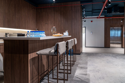 Modern pantry area at Azm Saudi Project featuring a sleek wooden counter, bar stools, and refreshments, designed for employee comfort and collaboration. Created by a Top Interior Fit-out Company in Riyadh and furnished by a Top Office Furniture Supplier in Saudi Arabia, this space enhances workplace wellbeing. منطقة مطبخ واستراحة عصرية في مشروع عزم السعودية من عمل أفضل مصمم داخلي في السعودية وتشطيب من أفضل شركة تنفيذ تشطيبات داخلية في الرياض. 5