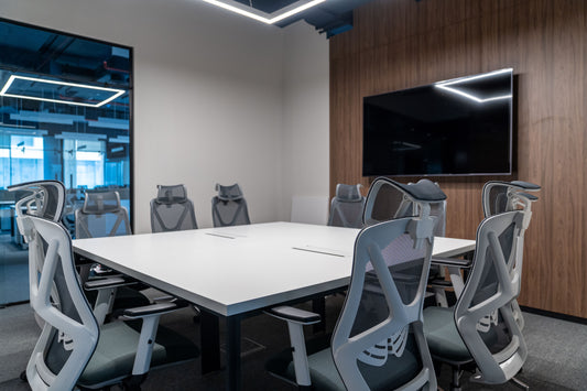 Modern meeting room at Azm Saudi Project, featuring ergonomic chairs, a large conference table, wood wall paneling, and mounted display screen for presentations. Designed by a Top Office Designer in Riyadh and furnished by a Top Office Furniture Supplier in Saudi Arabia, this room enhances collaboration. قاعة اجتماعات حديثة في مشروع عزم السعودية من تصميم أفضل مصمم مكاتب في السعودية وتشطيب من أفضل شركة تنفيذ تشطيبات داخلية في الرياض. 9