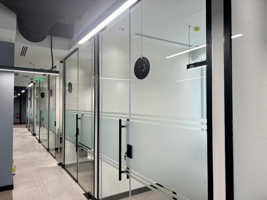 Sleek office corridor at GDC, one of the PIF companies, featuring frosted glass meeting rooms, suspended lighting, and modern flooring – designed and executed by Atelier 21 KSA, Top Office Designer and Interior Designer in Saudi Arabia and Riyadh. ممر مكتبي أنيق في مشروع GDC إحدى شركات صندوق الاستثمارات العامة، يضم غرف اجتماعات بزجاج بلوري وإضاءة معلقة وأرضيات حديثة من تنفيذ مفن الرسام، مما يعكس تميزه كأفضل مصمم داخلي ومورد أثاث ومصمم مكاتب في السعودية والرياض. 9