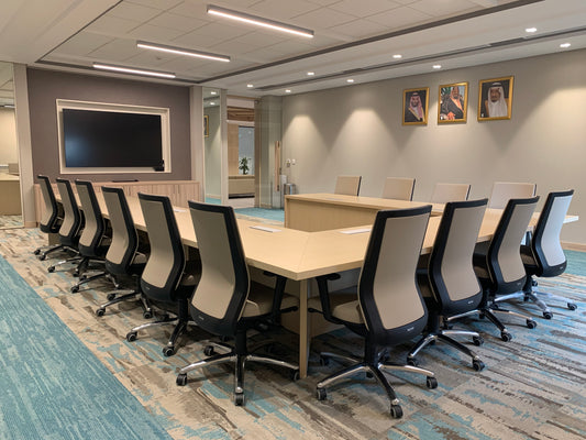 Spacious U-shaped meeting room with modern ergonomic chairs, light wood conference tables, wall-mounted screen, and royal portraits – designed by Atelier 21 KSA, Top Interior Designer, Office Designer, Furniture Supplier, and Interior Fit-out Company in Saudi Arabia and Riyadh. قاعة اجتماعات على شكل U، بطاولات خشبية وكراسي مريحة وتصميم عصري من تنفيذ مفن الرسام، أفضل شركة تصميم داخلي وتنفيذ تشطيبات مكتبية في السعودية والرياض. 9