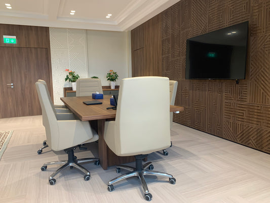 Modern small meeting room featuring a wood-finished wall, large screen, elegant beige chairs, and wooden meeting table – designed by Atelier 21 KSA, Top Interior Designer, Office Designer, Furniture Supplier, and Interior Fit-out Company in Saudi Arabia and Riyadh. غرفة اجتماعات صغيرة بتصميم حديث، حائط مزخرف وخشب طبيعي، طاولة اجتماعات، وكراسي جلد أنيقة من تنفيذ مفن الرسام، أفضل شركة تصميم داخلي وتشطيب في السعودية والرياض. 8