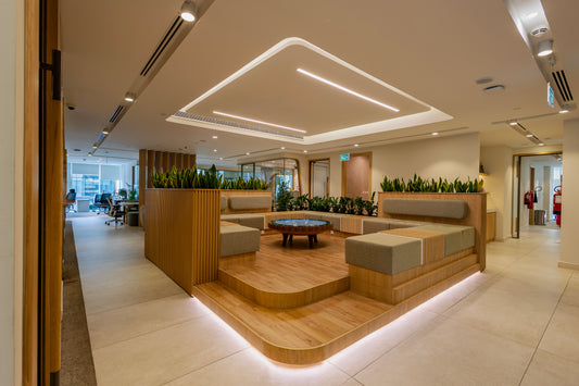 Modern breakout lounge at Azm Saudi Project, featuring raised wooden platform seating, integrated greenery, and contemporary lighting design, creating a collaborative and relaxing workspace. Executed by a Top Interior Designer in Riyadh and furnished by a Top Office Furniture Supplier in Saudi Arabia, it combines elegance and functionality. منطقة استراحة عصرية في مشروع عزم السعودية من عمل أفضل مصمم داخلي في السعودية وتشطيب من أفضل شركة تنفيذ تشطيبات داخلية في الرياض. 13