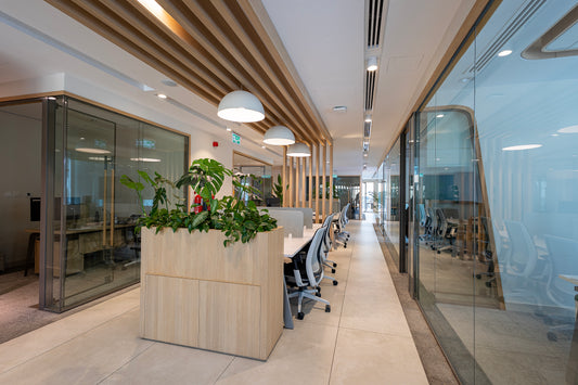 Open office corridor at Azm Saudi Project, featuring ergonomic workstations, glass-partitioned meeting rooms, greenery accents, and modern ceiling lighting for a vibrant workplace design. Executed by a Top Interior Designer in Riyadh and furnished by a Top Office Furniture Supplier in Saudi Arabia, it enhances collaboration and productivity. ممر مكاتب مفتوحة في مشروع عزم السعودية من عمل أفضل مصمم مكاتب في السعودية وتشطيب من أفضل شركة تنفيذ تشطيبات داخلية في الرياض. 14