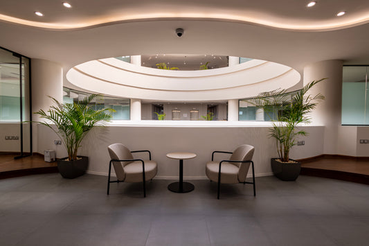 Modern office seating area with beige chairs, round coffee table, indoor plants, and architectural ceiling design by Atelier 21 KSA – مفن الرسام. Best interior fit-out in Riyadh, top office furniture supplier, top interior designer, افضل شركة تشطيبات داخلية، أفضل مورد أثاث مكتبي في السعودية 15