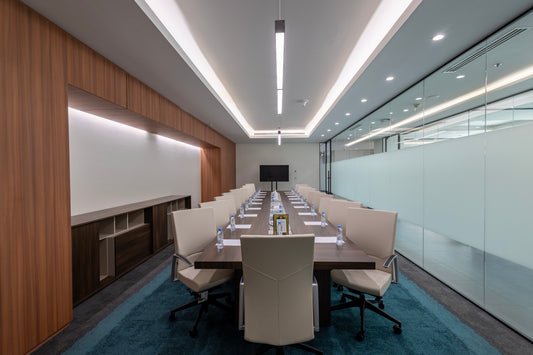 Modern conference room with long wooden meeting table, leather chairs, and glass walls, designed by Atelier 21 KSA – مفن الرسام, top office furniture supplier and top interior designer in Riyadh, Saudi Arabia – قاعة اجتماعات حديثة تحتوي على طاولة خشبية طويلة، كراسي جلدية، وجدران زجاجية من مفن الرسام، أفضل مورد أثاث مكتبي وأفضل مصمم داخلي في الرياض، السعودية 7