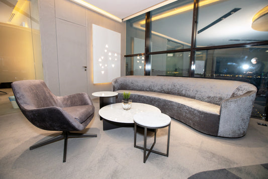 Modern office seating area with curved velvet sofa, lounge chair, marble coffee tables, and floor-to-ceiling windows by Atelier 21 KSA, top interior designer in Saudi Arabia – منطقة جلوس مكتبية عصرية تحتوي على كنبة مخملية منحنية، كرسي مفرد، طاولات قهوة من الرخام، ونوافذ ممتدة من الأرض إلى السقف من تصميم مفن الرسام، أفضل مصمم داخلي في السعودية 19