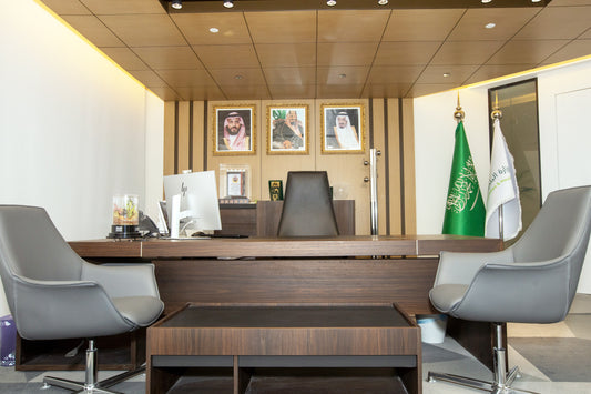 Modern executive government office with dark wood desk, grey chairs, Saudi leadership portraits, and ministry flags by Atelier 21 KSA, top interior designer in Saudi Arabia – مكتب حكومي تنفيذي عصري يحتوي على مكتب خشبي داكن، كراسي رمادية، صور قيادات المملكة، وأعلام الوزارة من تصميم مفن الرسام، أفضل مصمم داخلي في السعودية 18
