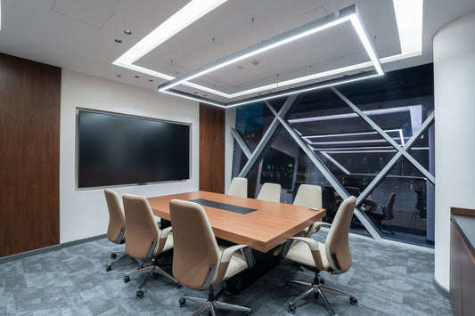 Modern conference room with wooden table and chairs, large screen on the wall by Atelier 21 KSA, top office furniture supplier in Riyadh – غرفة اجتماعات عصرية تحتوي على طاولة وكراسي خشبية، وشاشة كبيرة على الحائط من مفن الرسام، أفضل مورّد أثاث مكتبي في الرياض 5