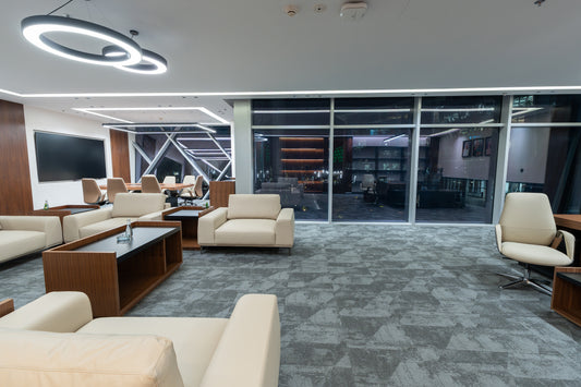 Modern office lounge with beige sofas, coffee tables, and large windows by Atelier 21 KSA, top furniture supplier in Riyadh – صالة مكتب عصرية تحتوي على كنبات بيج، طاولات قهوة، ونوافذ كبيرة من مفن الرسام، أفضل مورّد أثاث مكتبي في الرياض 6