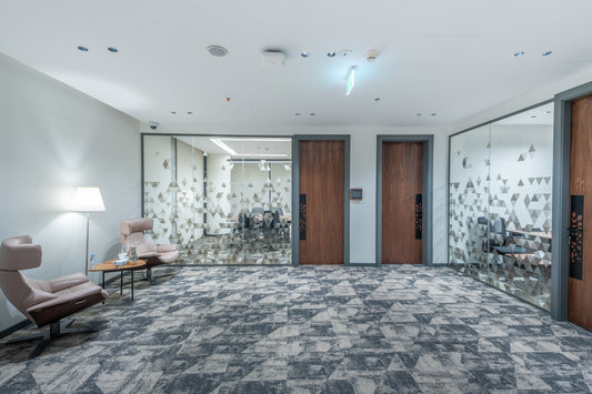 Modern office hallway with patterned carpet, wooden doors, and chairs by Atelier 21 KSA, top interior designer in Saudi Arabia – ممر مكتب عصري يحتوي على سجادة بنقشة مميزة، أبواب خشبية، وكراسي من مفن الرسام، أفضل مصمم داخلي في السعودية 8