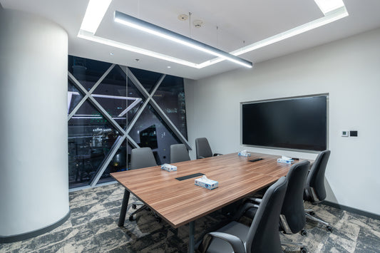 Modern conference room with a wooden table, chairs, and a large screen on the wall by Atelier 21 KSA, top office furniture supplier in Riyadh – غرفة اجتماعات عصرية تحتوي على طاولة خشبية، كراسي، وشاشة كبيرة على الحائط من مفن الرسام، أفضل مورّد أثاث مكتبي في الرياض 9