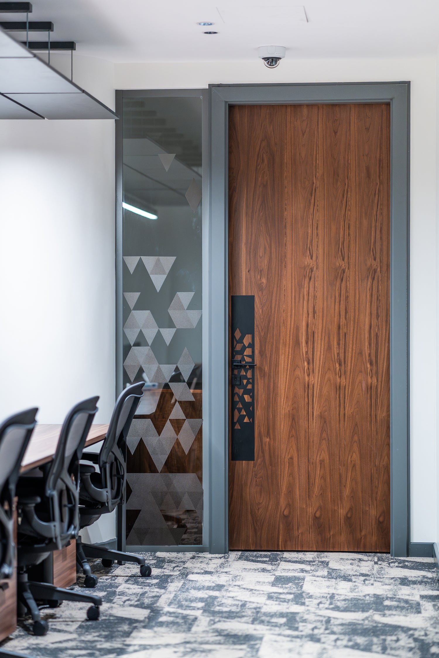 Wooden door in an office setting with chairs and a table by Atelier 21 KSA, top interior designer in Saudi Arabia – باب خشبي في مساحة مكتبية تحتوي على كراسي وطاولة من مفن الرسام، أفضل مصمم داخلي في السعودية