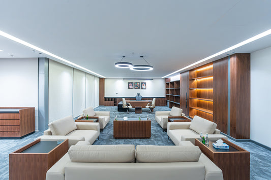 Modern office lounge with beige sofas, wooden tables, and bookshelves by Atelier 21 KSA, top furniture supplier in Riyadh – صالة مكتب عصرية تحتوي على كنبات بيج، طاولات خشبية، ورفوف كتب من مفن الرسام، أفضل مورّد أثاث مكتبي في الرياض 3
