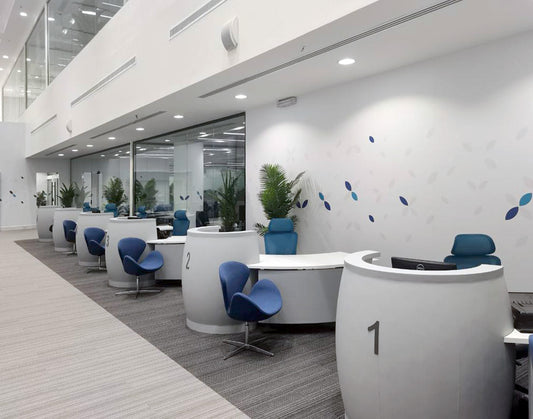 A modern, minimal reception area at Saudi Development Bank furnished by Atelier 21 KSA, featuring curved white desks, ergonomic blue chairs, and clean architectural lines. This project reflects the expertise of the Top Interior Designer in Saudi Arabia and the Top Furniture Supplier in Riyadh, combining form and function. أفضل مصمم داخلي في السعودية، وأفضل مورد أثاث مكتبي في الرياض، بتنفيذ عالي الجودة من مفن الرسام – أفضل شركة تنفيذ تشطيبات داخلية في السعودية. 1