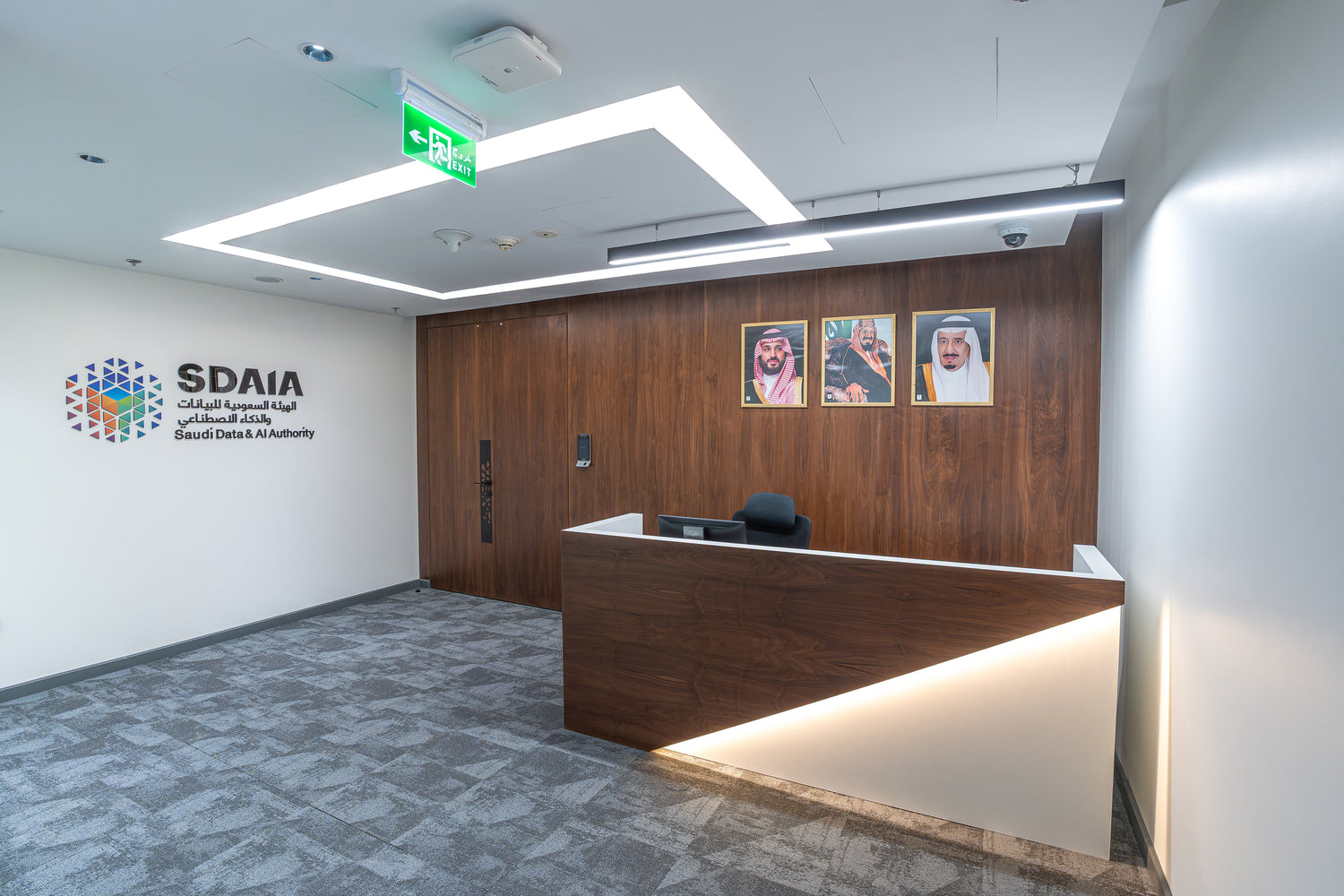 Modern office interior with reception desk and SDAIA logo on wall by Atelier 21 KSA, top interior designer in Saudi Arabia – تصميم داخلي عصري لمكتب يحتوي على مكتب استقبال وشعار الهيئة السعودية للبيانات والذكاء الاصطناعي (سدايا) على الحائط من مفن الرسام، أفضل مصمم داخلي في السعودية