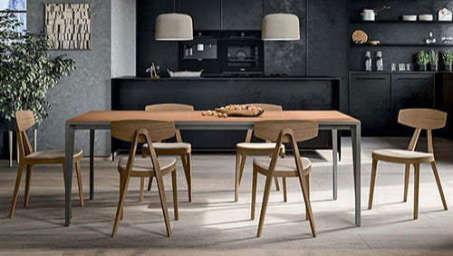 Modern kitchen with wooden dining table and chairs, dark cabinets, and a gray floor.