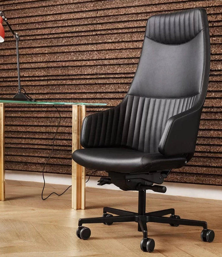 Black office chair in front of a desk with a laptop against a wooden paneled wall.
